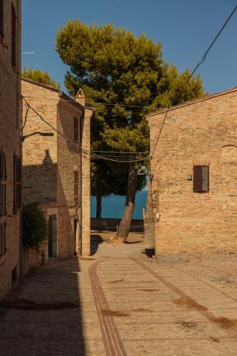 an alley between two brick buildings with a tree in the background at Castello Di Marà in Cupra Marittima