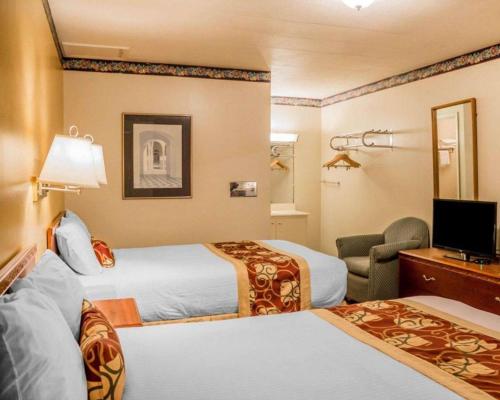 a hotel room with two beds and a television at Rodeway Inn Kalkaska in Kalkaska