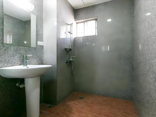 a bathroom with a sink and a shower with a mirror at E Moon Hotel in Taichung