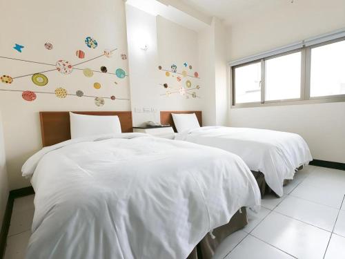 two beds with white sheets in a room with a window at E Moon Hotel in Taichung
