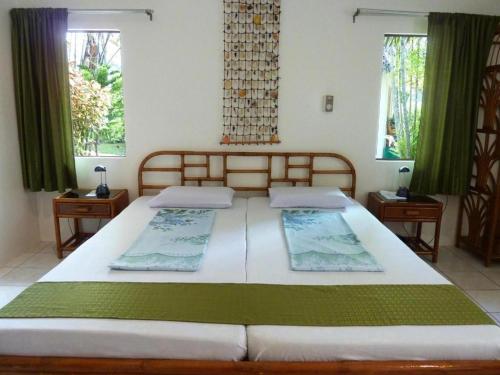 a large bed in a room with two windows at Marcosas Cottages Resort in Basdiot