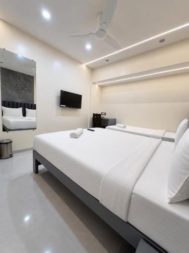 a bedroom with a large white bed and a tv at Lake Bloom Residency in Mumbai