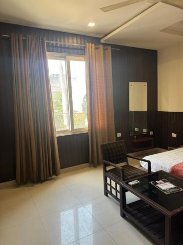 a bedroom with a bed and a coffee table and a window at Hotel Corbett Inn in Rudrapur