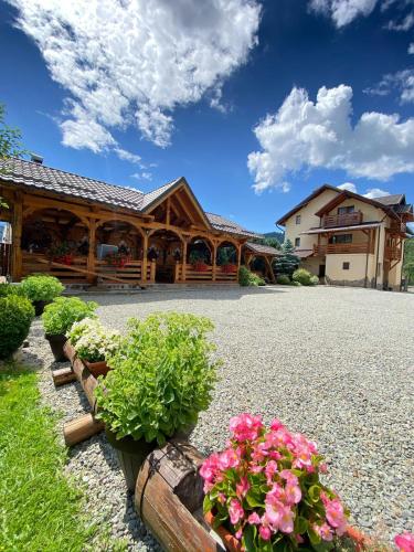 a house with flowers in front of a building at Pensiunea CARMEN Borșa in Borşa