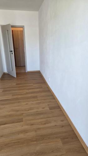 an empty room with a wooden floor and white walls at Apartmán Topolová 1146 in Milovice