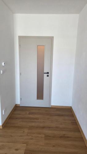 an empty room with a white door and a wooden floor at Apartmán Topolová 1146 in Milovice