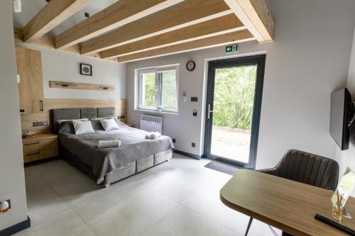 a bedroom with a bed and a table and a window at Serce Lasu - Hotel z Duszą i Energią Kamieni in Czarna