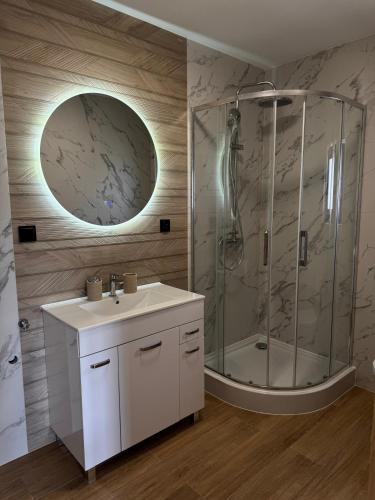 a bathroom with a shower and a sink and a mirror at Koperkowe Domki Zakopane in Zakopane