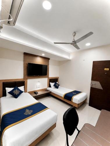 a bedroom with two beds and a flat screen tv at TRPOTELS Formerly Hotel Sagar in Gwalior