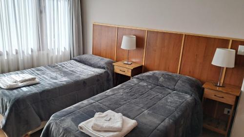 two beds in a hotel room with towels on the bed at Departamento Dina Huapi Bariloche in Dina Huapi