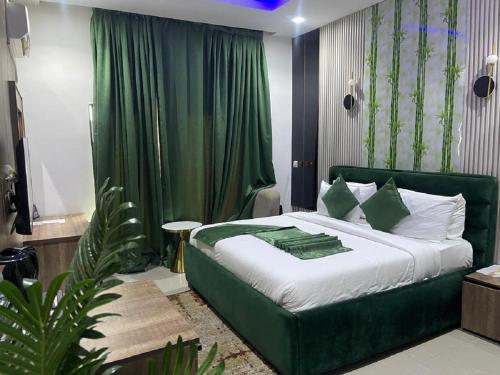 a bedroom with a green bed with a green curtain at Emirates Star Hotel & Suites in Asaba
