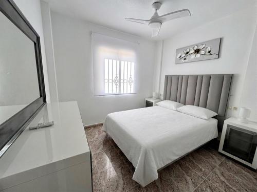a white bedroom with a bed and a window at La Macarena Torrevieja in Torrevieja