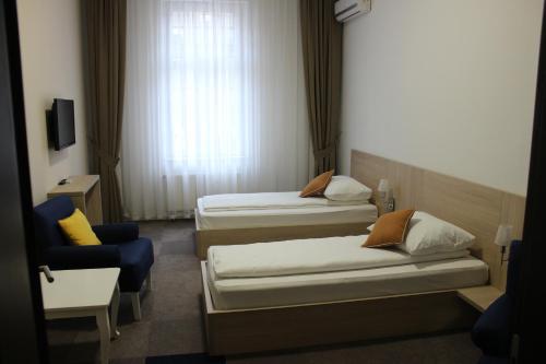two beds and a chair in a hotel room at Hotel Story in Sarajevo