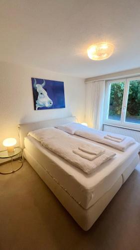 a large white bed in a room with a window at Chalet Steinbock Wengen in Wengen