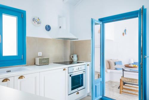 a kitchen with white cabinets and a blue door at Maison Mariel in Skopelos Town