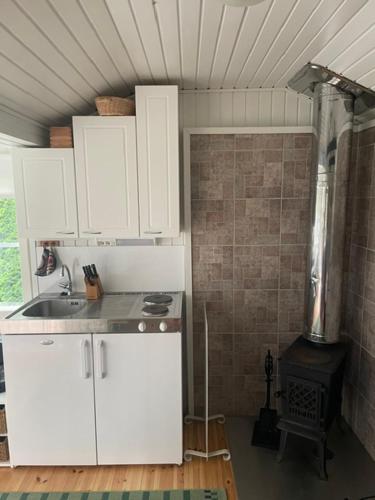 a kitchen with white cabinets and a stove at Pikkumökki Sveastugan in Rövik