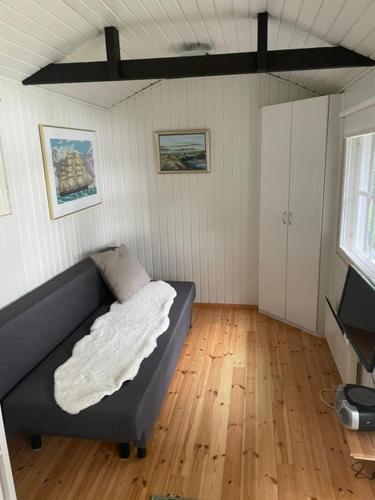 a living room with a couch and a wooden floor at Pikkumökki Sveastugan in Rövik