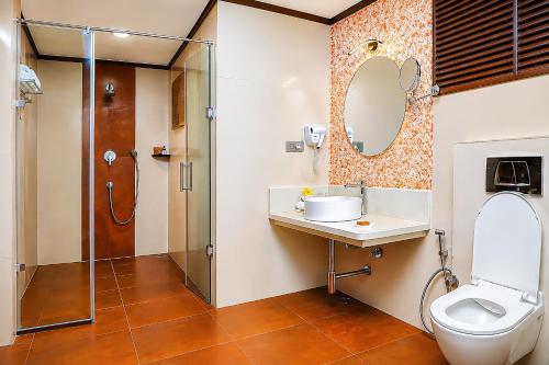 a bathroom with a toilet and a sink and a shower at Silent Shores Resort & Spa in Mysore