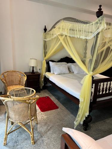a bedroom with a canopy bed and a chair at Belgi Guest House in Balapitiya