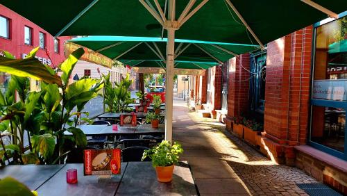 an outdoor patio with tables and a green umbrella at Tommel Apartments - Boardinghouse in Haldensleben