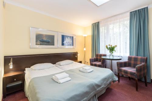 a hotel room with a bed and a table and chairs at Resort Plaza Spa in Darlowko