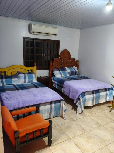 a bedroom with two beds and a chair in it at Chacara barro branco in Foz do Iguaçu