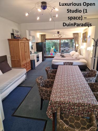a hotel room with three beds and a kitchen at DuinVliet - Zandvoort Dunes & Free Parking in Bentveld