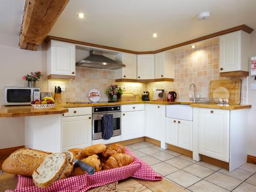 a kitchen with white cabinets and a basket of bread at Rowan Cottage - Uk4187 in Hazlehead Bridge
