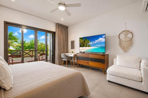 a bedroom with a bed and a television and a couch at Casa Seven Ocean Front with Private C hef Included in Isla Mujeres