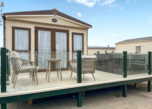 a house with two chairs and a table on a deck at Whitehouse Holiday Park in Abergele
