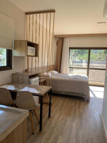 a bedroom with a bed and a table with chairs at Tons de Mar Apart Hotel in Ubatuba