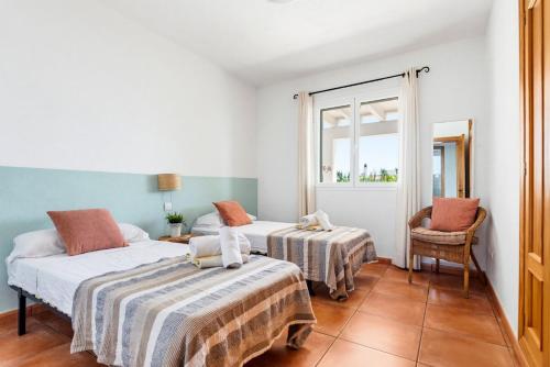 a bedroom with two beds and a chair and a window at Villa Casa Nova by 3VILLAS in Sant Lluis