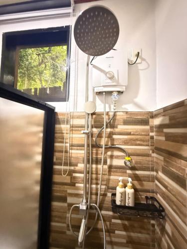 a shower in a bathroom with a wooden wall at Fabregas Beach Cottages in El Nido