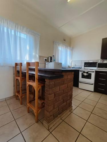 a kitchen with a table and two wooden chairs at Melvillas in Louis Trichardt