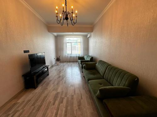 a living room with a couch and a television at Caspian Boulevard Residence in Sumqayıt