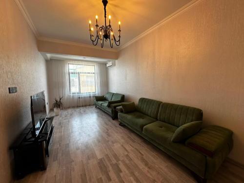 a living room with a green couch and a chandelier at Caspian Boulevard Residence in Sumqayıt