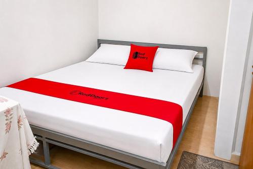 a bed with a red pillow on top of it at RedDoorz at Jatisampurna 