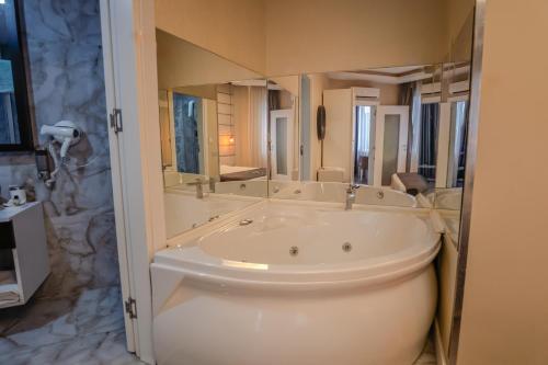 a bathroom with a tub and a large mirror at Siete Hotel in Antalya