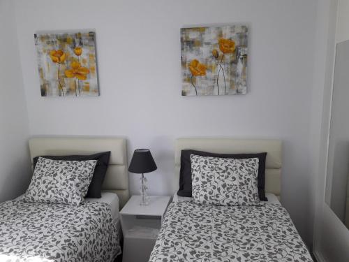プエルト・デル・カルメンにあるApartamento Club Valenaのベッドルーム1室(ベッド2台付)が備わります。壁には絵画が2点飾られています。