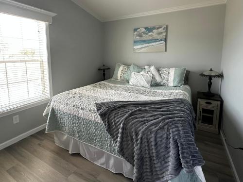 a bedroom with a bed with a blanket and a window at Lake Front, Beach Retreat in Fort Myers Beach