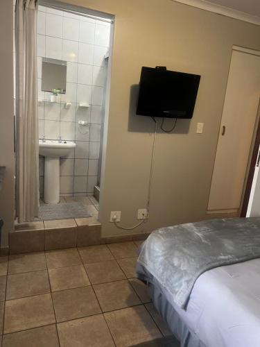 a bedroom with a bed and a bathroom with a television at Serendipity Guest House in Richards Bay