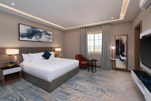 a hotel room with a bed and a flat screen tv at Warwick Al Baha Hotel in Baljurashi