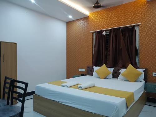 a bedroom with a large bed with yellow and white pillows at Hotel Rudra Heritage in Jasidih