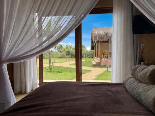a bedroom with a bed and a large window at Pousada Nitxi Awêry in Caraíva