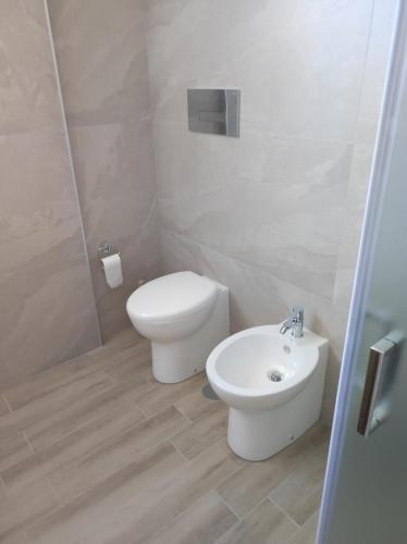 a white bathroom with a toilet and a sink at Residence Mancini - Cilento Home & Sunset in Rocca Cilento
