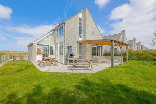 a house with a picnic table and two benches at Villa Mooy met sauna - Landal park Ooghduyne Julianadorp aan Zee in Julianadorp