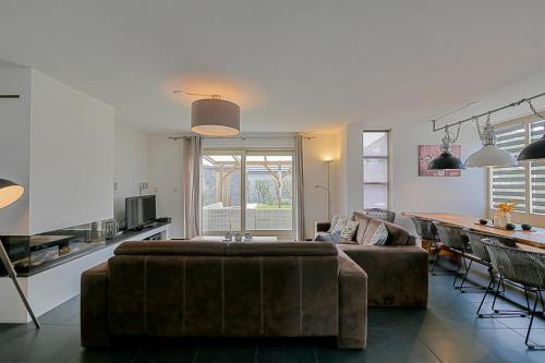 a living room with a couch and a table at Villa Mooy met sauna - Landal park Ooghduyne Julianadorp aan Zee in Julianadorp