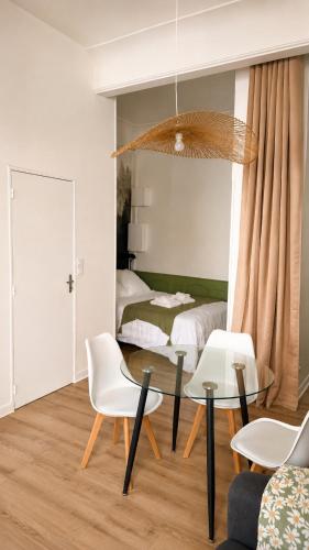 a living room with a table and chairs and a bed at Charmant appartement dans le centre ville in Bagnères-de-Bigorre