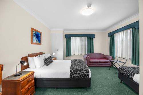 a hotel room with a bed and a chair at Maynestay Motel in Gunnedah