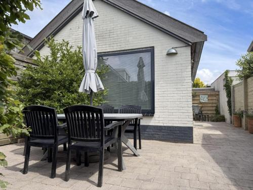 a table with chairs and an umbrella on a patio at Texelheerlijk 1 in De Koog